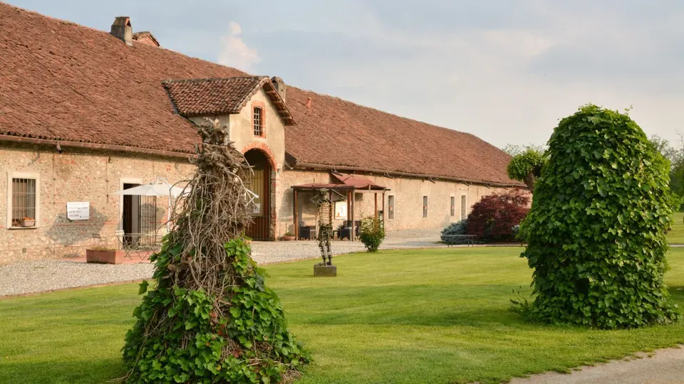 La cascina in mattoni e coppi vista dal prato, con il portico d'ingresso